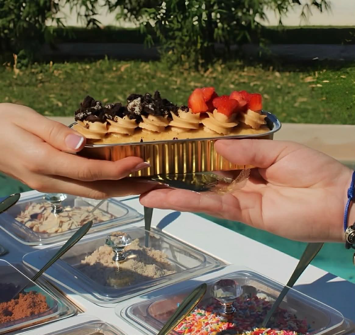 Freshly topped mini dessert being served at an outdoor event
