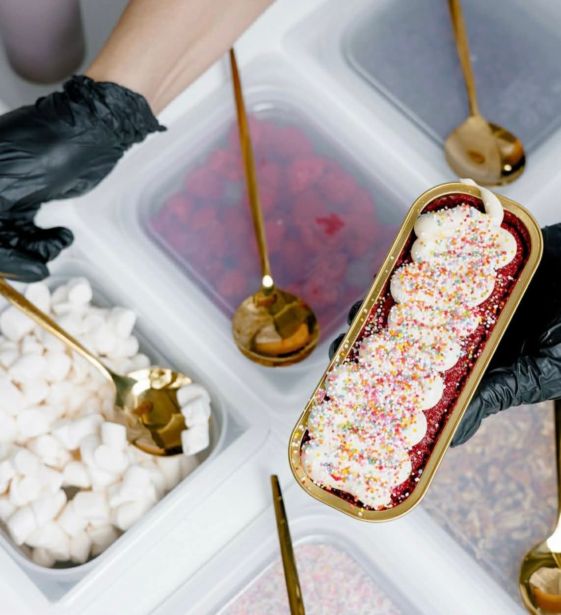 Behind the scenes: assembling a mini dessert with sprinkles, marshmallows, and gold serving spoons