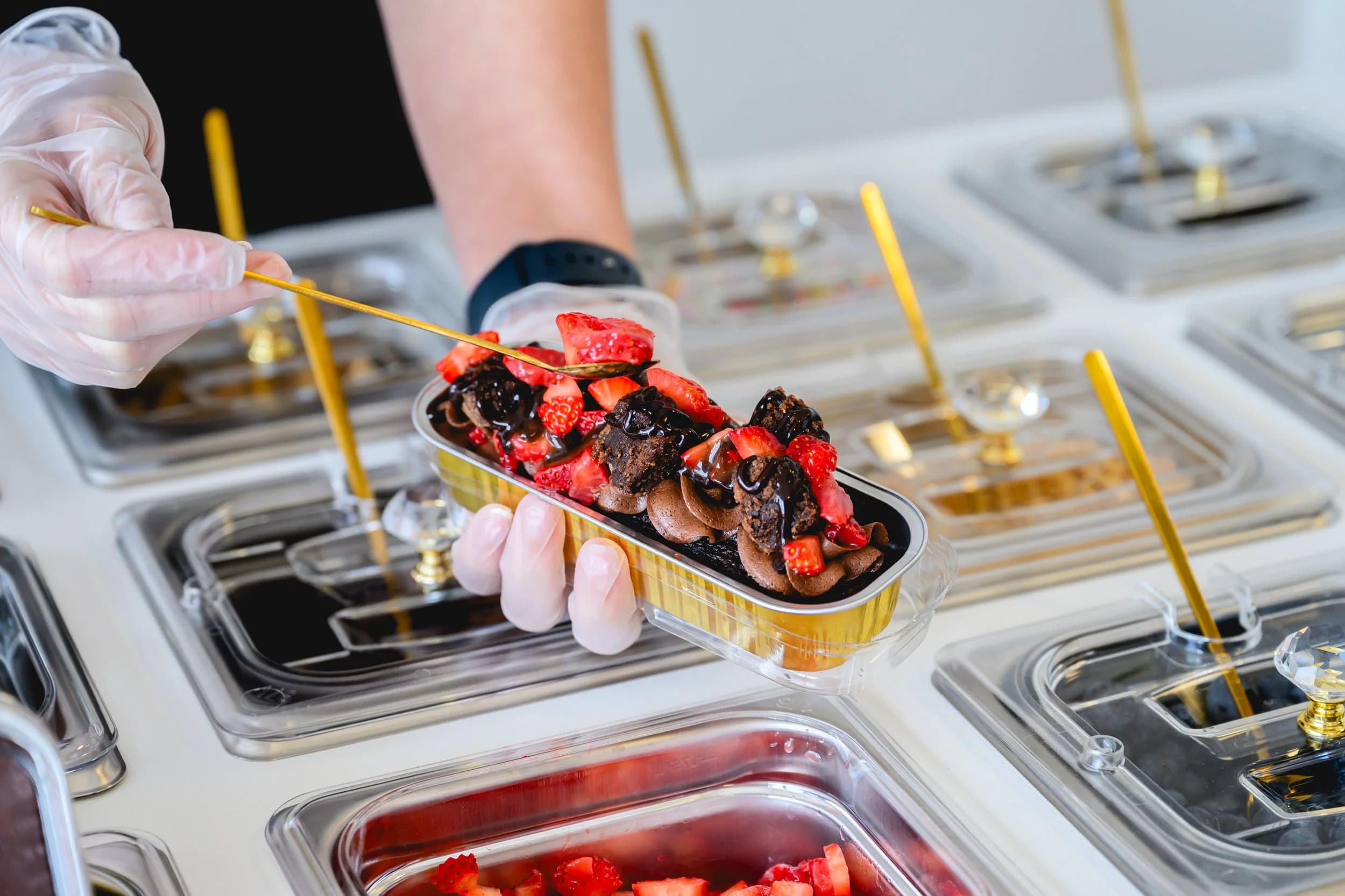Close-up of a mini chocolate dessert boat being plated with fresh strawberries